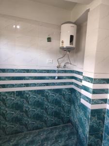 a bathroom with blue and white tiles and a soap dispenser at Katha Inn in Manāli