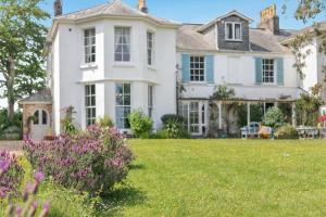 a white house with a yard with purple flowers at 4 Bed in Barnstaple oc-n34877 in Tawstock
