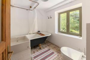 a bathroom with a tub and a toilet and a window at Klavze 28 in Most na Soči +86 photos