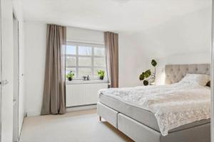 a white bedroom with a bed and a window at 80320-Ulfborg-Reberbanen-4 in Ulfborg