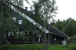 ein schwarzes Haus mit einer Veranda und Bäumen in der Unterkunft Trysil Alpin 16A Top location in Trysil