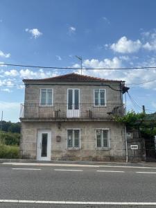 a stone house with a balcony on a street at Casa Viñao in Boborás