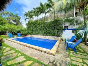 a pool with blue chairs next to a house at La Posada Azul Boutique Hotel Coco SA in San Juan del Sur