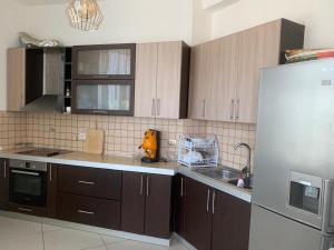 a kitchen with wooden cabinets and a stainless steel refrigerator at Vila Era in Shëngjin