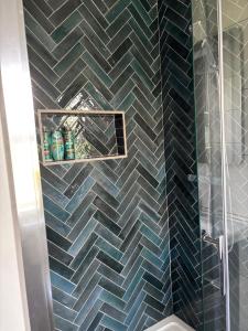 a bathroom with a glass shower with blue tiles at Beach view Bungalow in Spanish Point