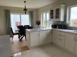 a kitchen with white cabinets and a table with chairs at Beach view Bungalow in Spanish Point