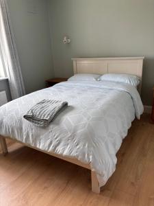 a white bed with a blanket and pillows on it at Beach view Bungalow in Spanish Point +5 photos