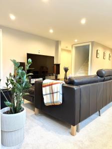 a living room with a black leather couch and a tv at Ivy s House in West Vancouver