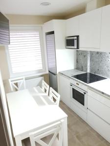 a kitchen with white cabinets and a white table and chairs at Ezerkrasts Daugavas 7 in Liepāja +13 photos