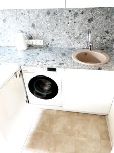 a kitchen with a sink and a washing machine at Ezerkrasts Daugavas 7 in Liepāja