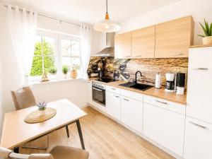 a kitchen with white cabinets and a wooden table at Ferienwohnung Rita Usedom in Korswandt