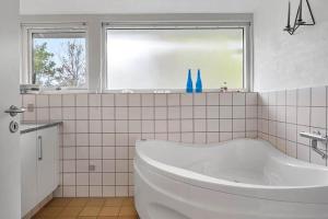 a white bathroom with a tub and a window at 1077-Thisted-Johns-Vej-33 in Klitmøller +15 photos
