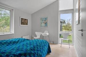 a bedroom with a bed and chairs and windows at 1077-Thisted-Johns-Vej-33 in Klitmøller
