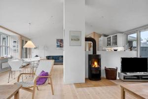 a living room with a fireplace and a dining room at 1077-Thisted-Johns-Vej-33 in Klitmøller