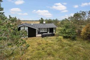 a small black house in the middle of a field at 1077-Thisted-Johns-Vej-33 in Klitmøller