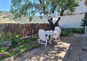 a table and chairs with an umbrella in a garden at Chalet antiguo reformado "El Mirador" in Hoyo de Pinares