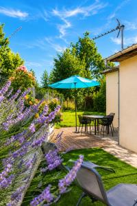 a patio with a table with an umbrella and purple flowers at Le petit paradis in Abbeville