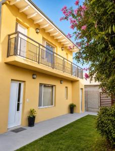 a yellow house with a balcony and a yard at Las lupinas pleno centro in Coronel Suárez