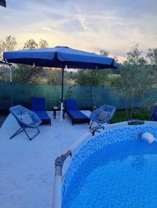 a swimming pool with a blue umbrella and chairs and a table at Tiny Loft House in Halkidiki in Nea Potidaea