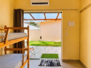 a bedroom with bunk beds and a door to a yard at Chalés & Suítes Praia Barequeçaba I Cozinha Compacta in São Sebastião