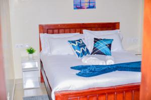 a bed with blue and white sheets and pillows at Savana Abode-Nakuru CBD in Nakuru +7 photos