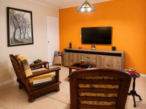 a living room with a flat screen tv on an orange wall at Barrio Aeropuerto depto 2 dormitorios en Río Grande in Río Grande
