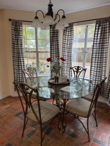 a dining room with a glass table and chairs at WildFlower Inn in Satsuma