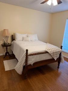a bedroom with a bed with white sheets and a fan at WildFlower Inn in Satsuma