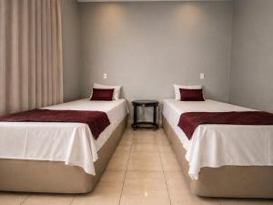 zwei Betten, die in einem Zimmer nebeneinander stehen in der Unterkunft Hotel dos Lagos in Alfenas