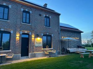 a brick building with chairs and an umbrella in the yard at Huys van Haeghe in Zoutleeuw