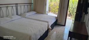 two beds in a hotel room with a window at Hotel San Carlos in Tizimín