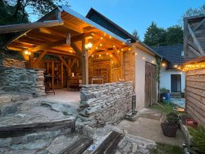 a patio with a stone wall and a wooden pergola at Chalupa U dančí obory in Hvozd