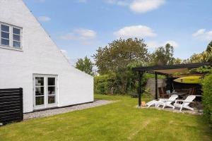 a white house with a patio with chairs and a surfboard at 20623-Samso-Besser-Hovedgade-9 in Besser