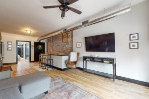 a living room with a couch and a tv on a wall at Steps to Dtwn & Rock River! Couples Retreat in Janesville