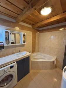 a bathroom with a tub and a sink and a washing machine at Kinga House in Keszthely +11 photos