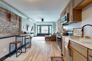an open kitchen and living room with a brick wall at Steps to Dtwn & Rock River! Couples Retreat in Janesville