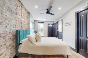 a bedroom with a brick wall and a bed with pillows at Steps to Dtwn & Rock River! Couples Retreat in Janesville