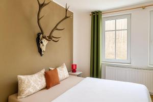 a bedroom with a white bed with antlers on the wall at Pension Waldfrieden in Thale