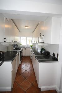 una cocina con armarios blancos y encimeras negras en Ash Grove House en Galway