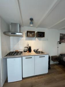 a kitchen with white cabinets and a sink at B&Beach Zandvoort in Zandvoort
