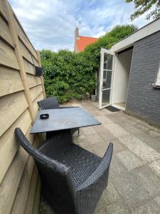a patio with a table and a wicker chair at B&Beach Zandvoort in Zandvoort