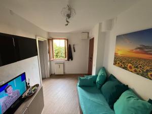 a living room with a green couch and a television at Vicolo dell'Orto in Montaione