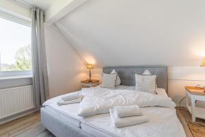 a bedroom with a bed with white sheets and a window at Ferienwohnung Deichblick Quartier Pellworm in Pellworm