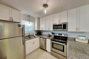 a kitchen with white cabinets and stainless steel appliances at Beachside Villas #413 in Seagrove Beach