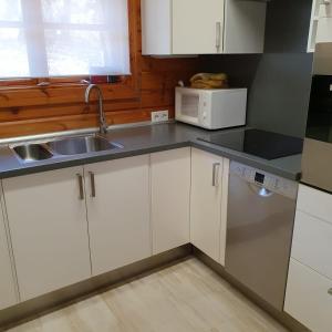 a kitchen with white cabinets and a sink and a microwave at Kleine Auszeit am Twistesee in Bad Arolsen