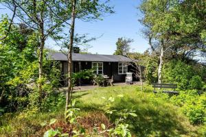 a black cabin in the woods with a yard at 2236-Ringkobing-Fladsbjergvej-220 in Klegod