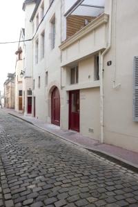 a cobblestone street with buildings with red doors at Beaune Sweet Home in Beaune