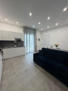 a living room with a black couch and a kitchen at Velù Apartment in Porto Viro