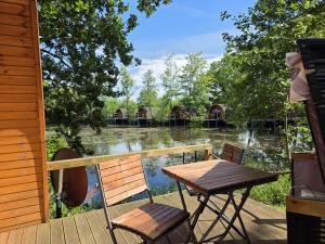 a table and chairs on a deck with a view of a lake at 13 Premium Camping Pod "Holmer See" in Silberstedt