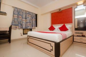 a bedroom with a bed with red pillows and a window at Super Hotel O Solitaire in Turambhe